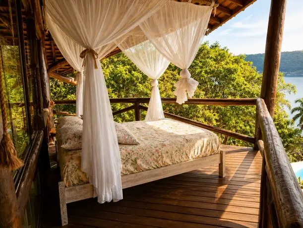 Cama com dossel na varanda, com vista para o mar