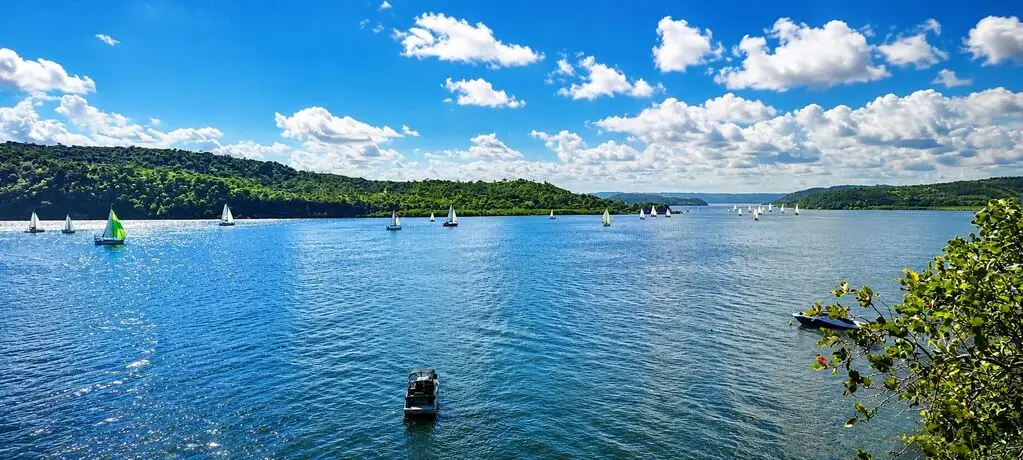Baía de águas calmas com barcos ao fundo