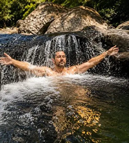 Participante em rio entre as pedras da mata